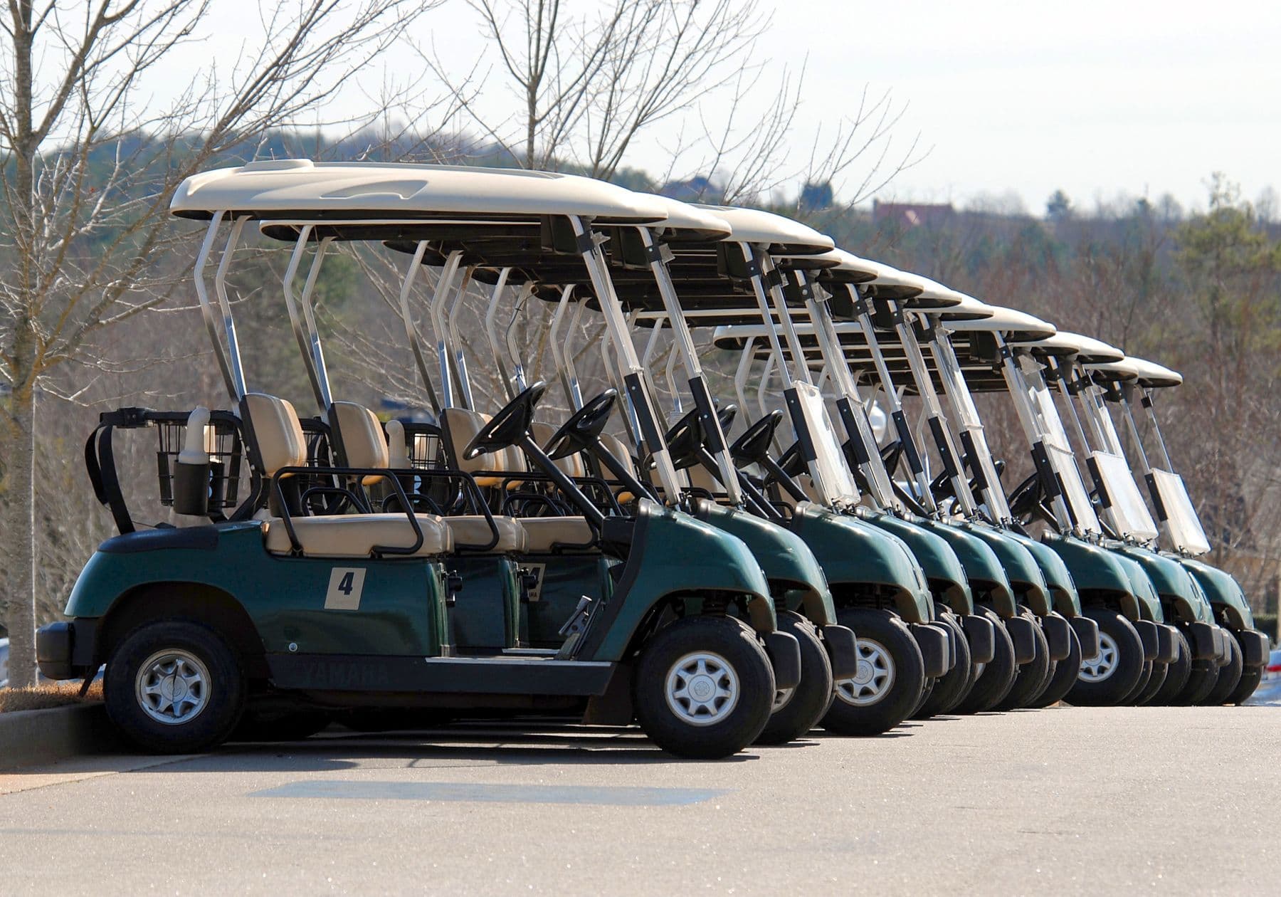 A line of green golf carts parked in a row